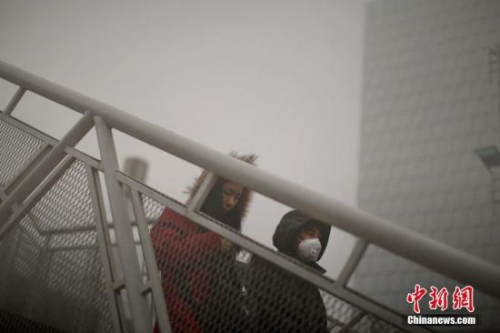 12月4日，戴着口罩的行人从天桥上走过。天津市气象台当日7时发布大雾橙色预警信号，天津大部分地区笼罩在大雾中，局部地区能见度低于200米。 <a target='_blank' href='http://www.chinanews.com/' _fcksavedurl='http://www.chinanews.com/'></table>中新社</a>记者 佟郁 摄