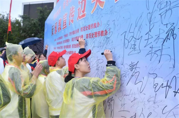 新一代边境青年人在反邪教宣传边关行活动墙签名。（广西反邪教网供图）